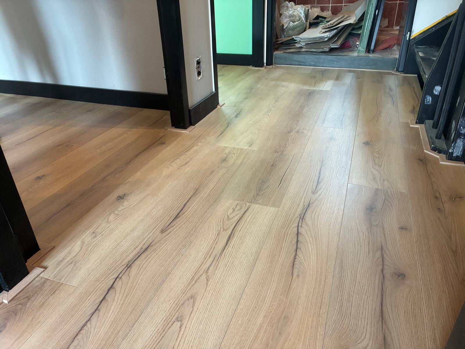 Rustieke eiken plankvloer met zwarte plinten in een woning in Borne