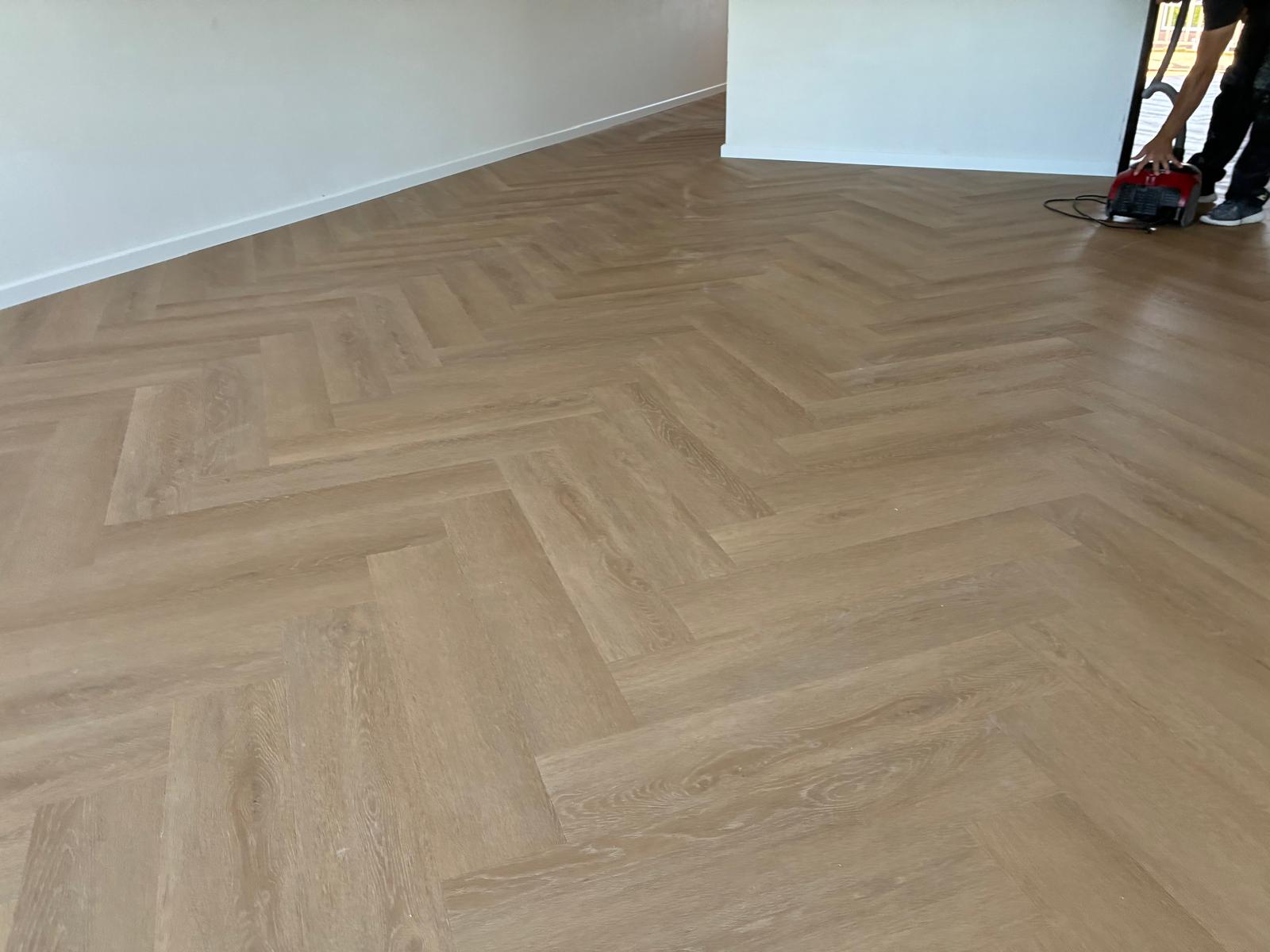 Lichte greige eiken visgraatvloer in een ruime woonkamer in Tubbergen