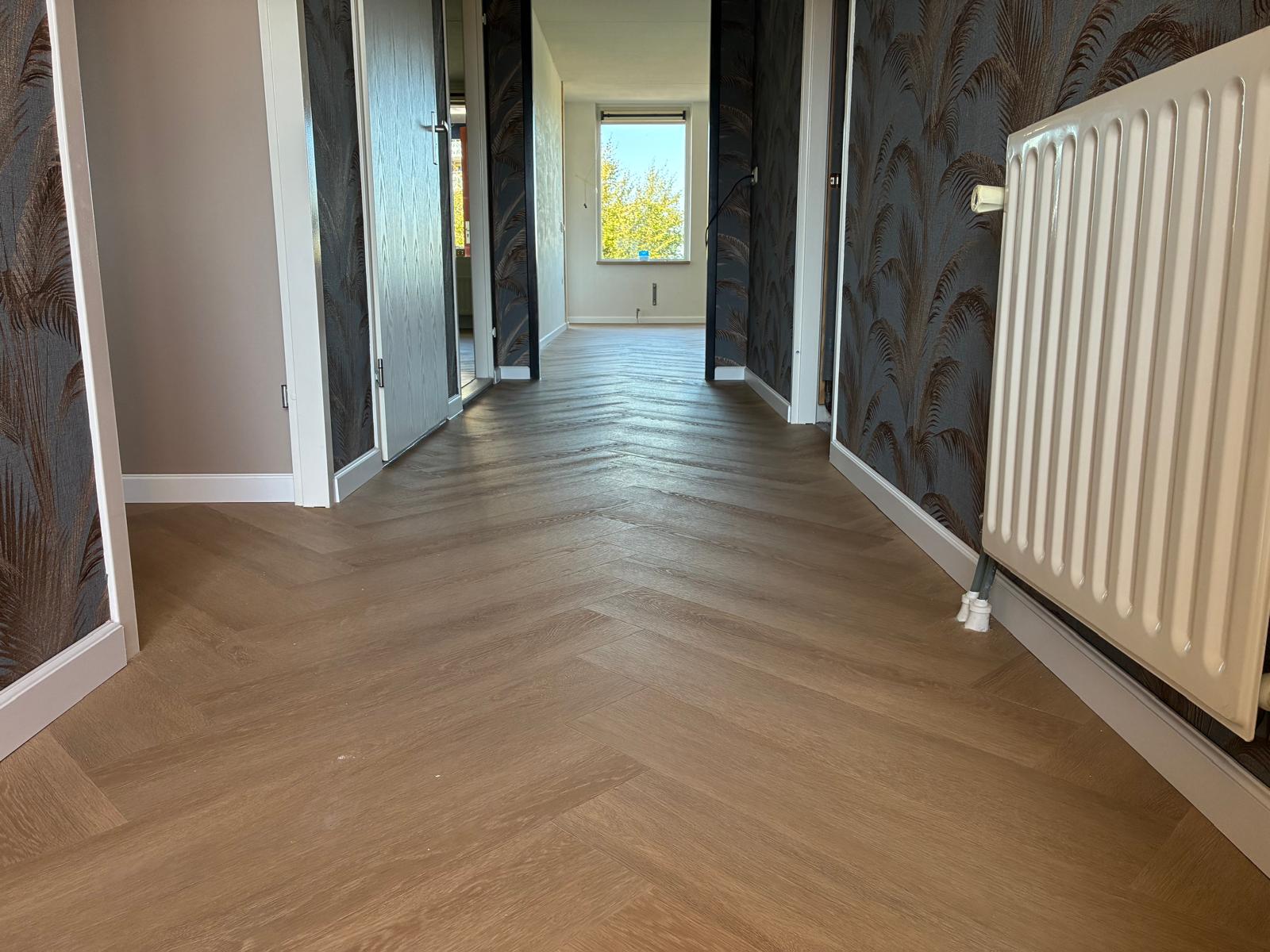 De gang met palmbladbehang, waar de visgraat doorloopt naar alle kamers