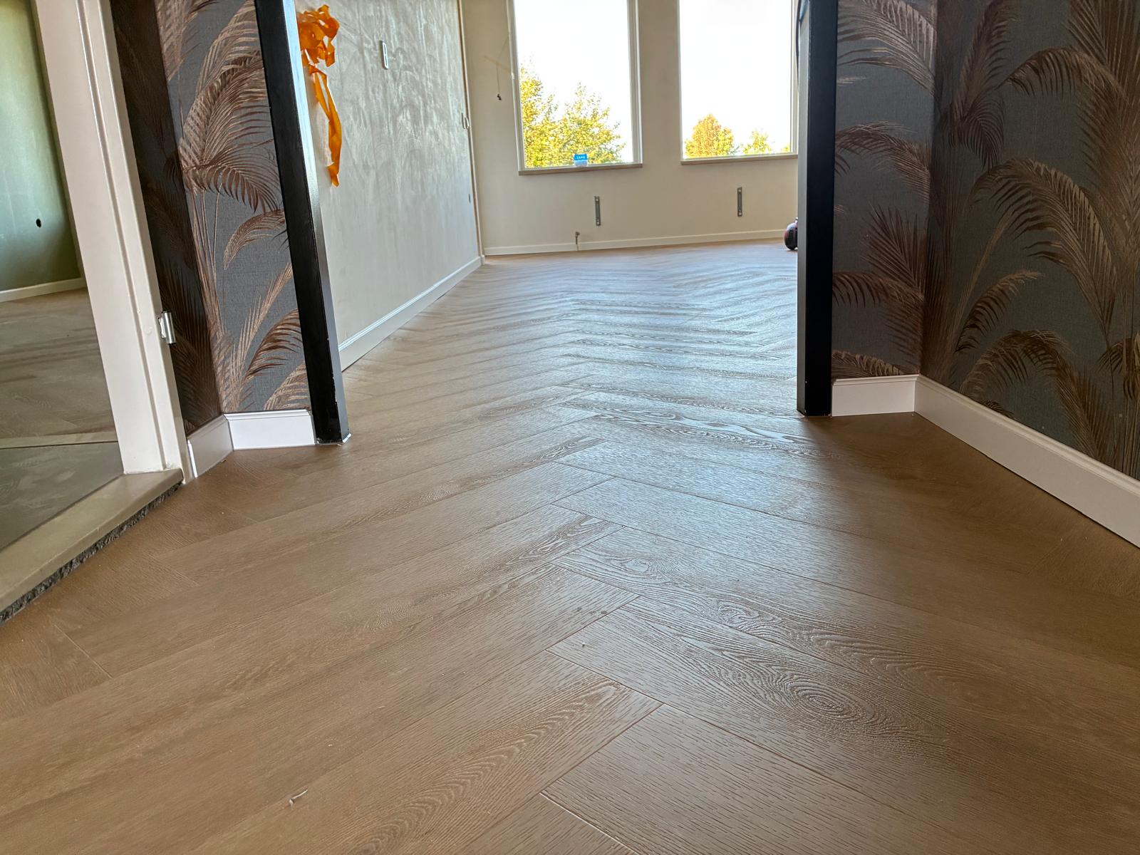 Warme eiken visgraatvloer in een woning in Hardenberg met palmbladbehang