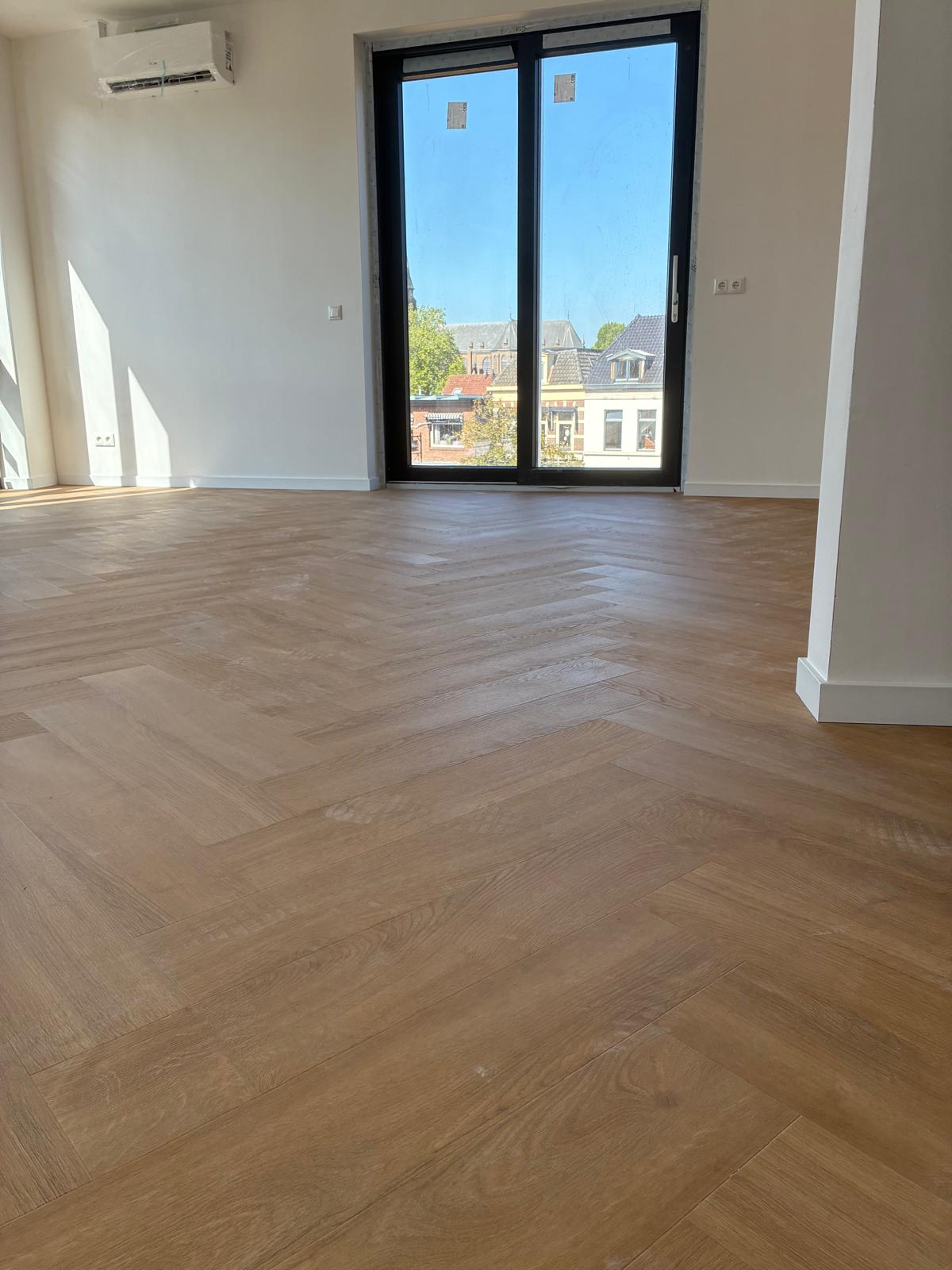 Naturel eiken visgraatvloer in een nieuw appartement in Oldenzaal met uitzicht op de stad